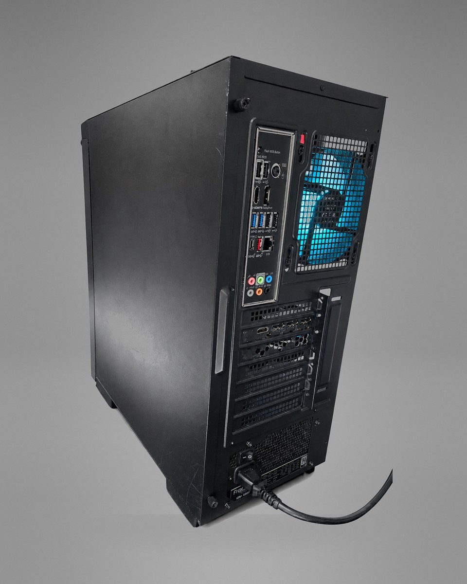 Rear angle of Midnight Circuit 001 from the left, showing the plain side panel, the motherboard port cluster and the blue-lit rear fan.